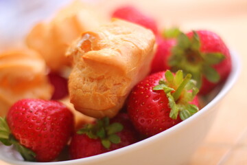 Fresh strawberries and profiteroles with ice cream in a white bowl
