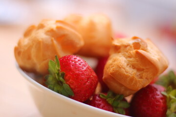 Fresh strawberries and profiteroles with ice cream in a white bowl