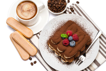 portion of Classic tiramisu dessert with raspberries, blueberries and cup of fresh hot espresso isolated on white background - clipping path