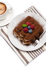 portion of Classic tiramisu dessert with raspberries, blueberries and cup of fresh hot espresso isolated on white background - clipping path