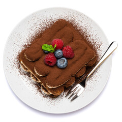 portion of Classic tiramisu dessert with raspberries and blueberries on ceramic plate isolated on white background - clipping path