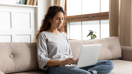 Woman relaxing on couch using laptop search information on internet. Freelance female do remote...