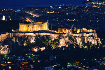 Fototapeta na wymiar Close view of Acropolis, Parthenon and Erechtheion, Philoppapos monument at night. City lights of Athens. Famous view of UNESCO world heritage site.