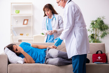 Obraz premium Two doctors visiting sick young man at home