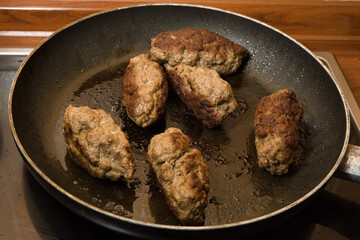 close up shot of cevapcici meat balls in a frying pan