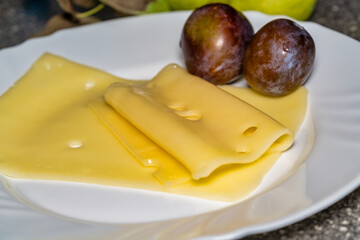 sliced cheese and plums on a white plate