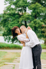 Fototapeta premium Man in love kisses a woman's neck on the background of the park.
