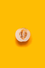 Ripe yellow half of a melon on a yellow background, vertical photo. Summer fruit concept