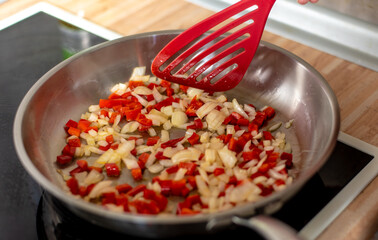 fried peppers and onions in a preheated pan, preparing a meal at home