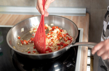 fried peppers and onions in a preheated pan, preparing a meal at home