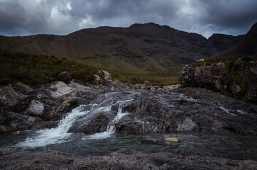 A waterfall in the Fairy Pools on the Isle of Skye under a stormy sky, Scotland, United Kingdom