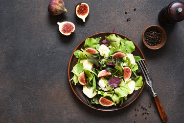 Mix salad with figs and brie cheese on a concrete background