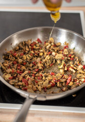 frying onions and peppers in a hot frying pan, adding oil during preparation