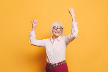 Happy elderly woman with white hair, round glasses wearing white blouse, red pants and leopard...