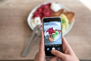 A food blogger takes photos of a home dinner with his phone