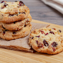 Home baked cookies on a wooden cutting board with paper. Cookies with chocolate and cranberries