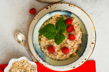 Delicious oatmeal porridge with ripe raspberries. Healthy and hearty Breakfast. The concept of diet and vegetarian food for a slim figure lifestyle