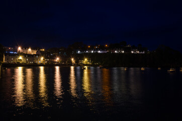 Fototapeta na wymiar City landscape,of Portree at night with the lights of lamppost reflected on the sea water, Isle of Skye, United Kingdom