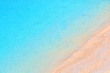 Empty sand beach with transparent sea water. View above. Mediterranean background.