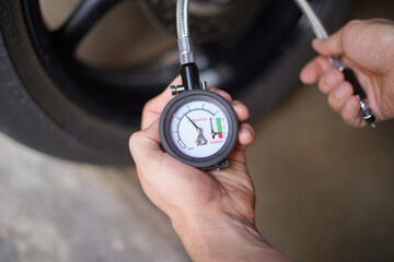 Man checking manually air pressure of motorcycle wheel before traveling