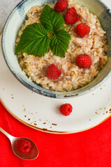 Delicious oatmeal porridge with ripe raspberries. Healthy and hearty Breakfast. The concept of diet and vegetarian food for a slim figure lifestyle