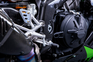 close up of a high performance sports motorcycle with carbon enclosing, looking onto the exhaust and gear shift pedals, motor engineering
