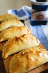Homemade baked empanadas and mate in the background 