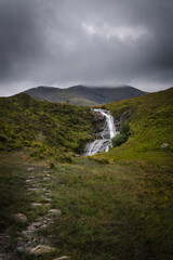 A nature landscape with a waterfall under a cloudy sky in the Isle of Skye, Scotland, United Kingdom