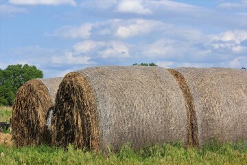 hay bales in the field in Kansas with blue sky and white clouds.
