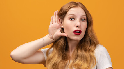 Young pretty woman with wavy redhead holding hand near ear