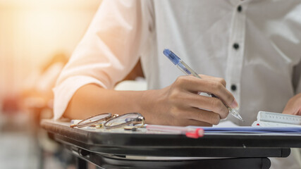 Exam at school with student's taking educational admission test in class, thinking hard, writing answer in university classroom, education and world literacy day concept