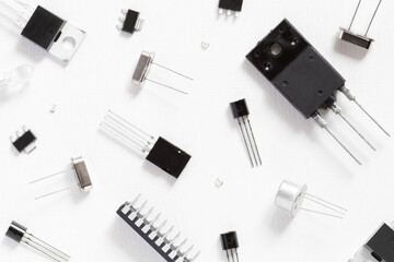 Black radio components close-up on a white background. There are transistors, microcircuits, LEDs, SMD components
