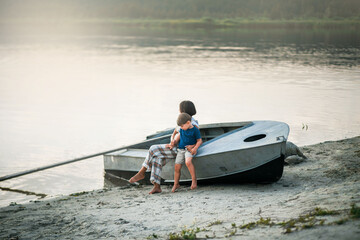 children are sitting on a boat near the lake on the shore and soft sunlight is shining on them