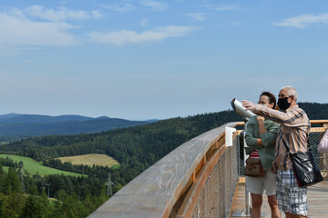 The family in protective masks on a trip on the tower at a height admires the surrounding nature
