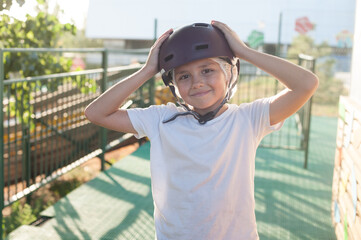 The boy takes off his helmet with a smile. Safe entertainment, a means of protection