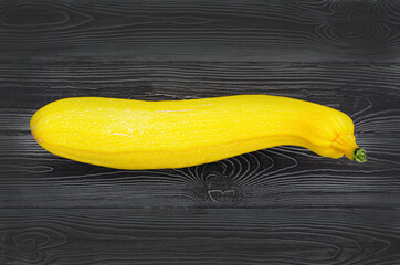 Yellow zucchini on a dark wooden background. New crop concept. Isolate, top view. Copy space. Banner.