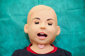 Head of lying training dummy imitating small child with open mouth and closed eyes