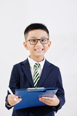 Portarit of joyful smiling Vietnamese kid in formalwear with folder writing in document