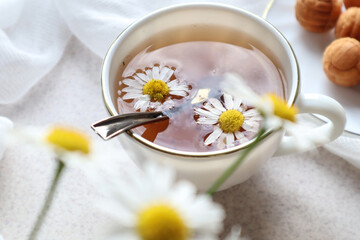Obraz na płótnie Canvas Two daisies in a Cup of chamomile tea, close-up, top view, bokeh-the concept of a good time and a delicious tea party