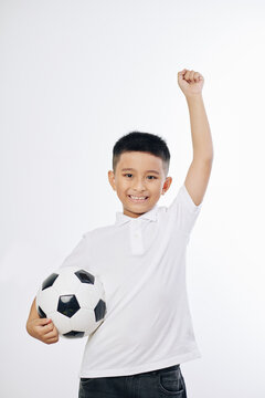 Portrait of smiling Vietnamese boy jumping with soccer ball in hand, isolated on white