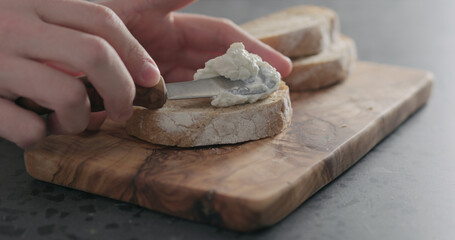 man hand spreading ricotta on slice of ciabatta