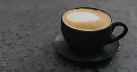 cappuccino in black cup on terrazzo countertop