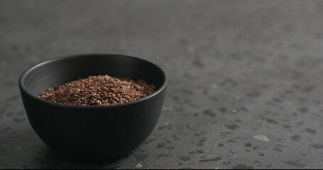 flaxseed in black bowl on terrazzo countertop with copy space