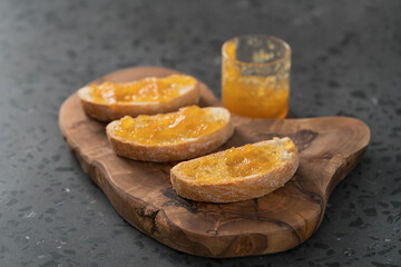 Ciabatta slices with orange marmalade on olive board