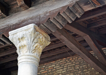 
white stone capital that supports the load-bearing structure of a roof with wooden elements