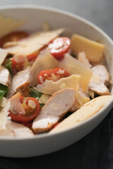 Fresh caesar salad with chicken and cherry tomatoes in white bowl