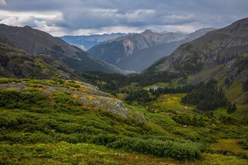 Mountain pass in the summer with green grass and storm clouds during a hike in colorado