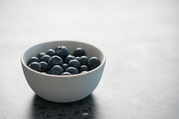 Fresh ripe blueberries in white bowl on concrete background with copy space