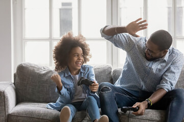 Overjoyed african american family involved in video game competition at home, excited emotional...