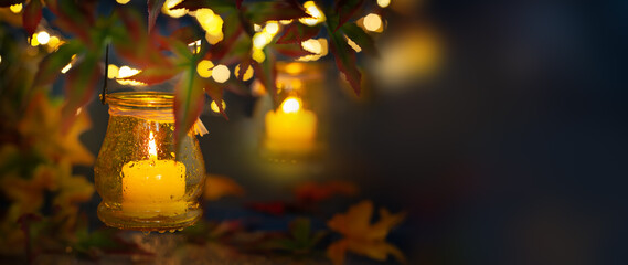 Festive autumn lighting decor. Candle in a jar with rain drop, hanging on tree branches for night...